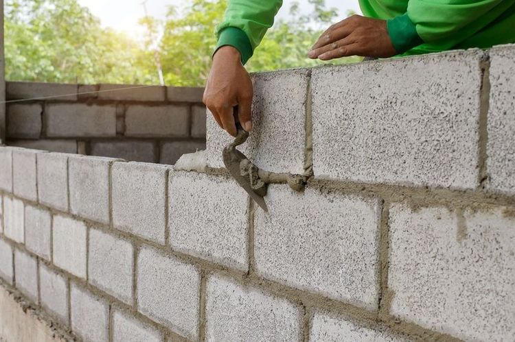 masonry_worker_make_concrete_wall_by_cement_block_and_plaster_at_construction_site
