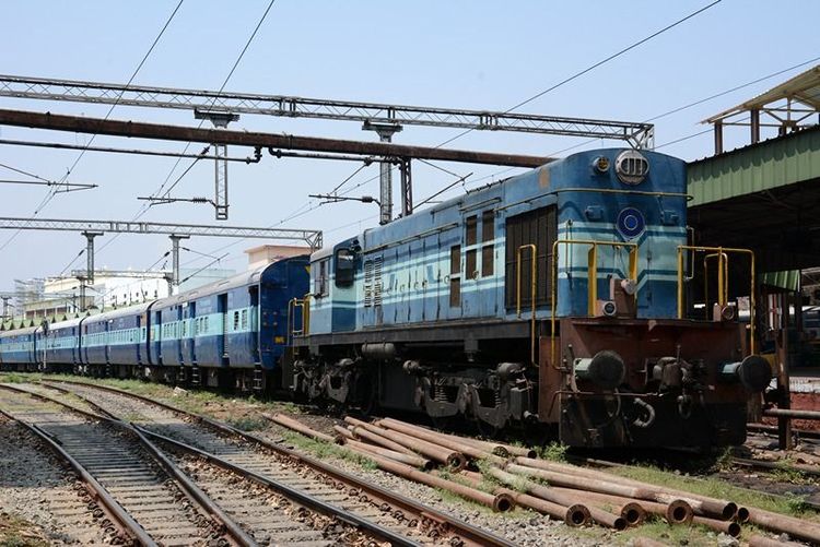 A_diesel_locomotive_hauling_a_passenger_train_through_a_railway_station_in_India.