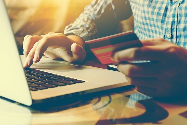 man_typing_laptop_keyboard_and_holding_credit_card_at_home_with_online_shopping
