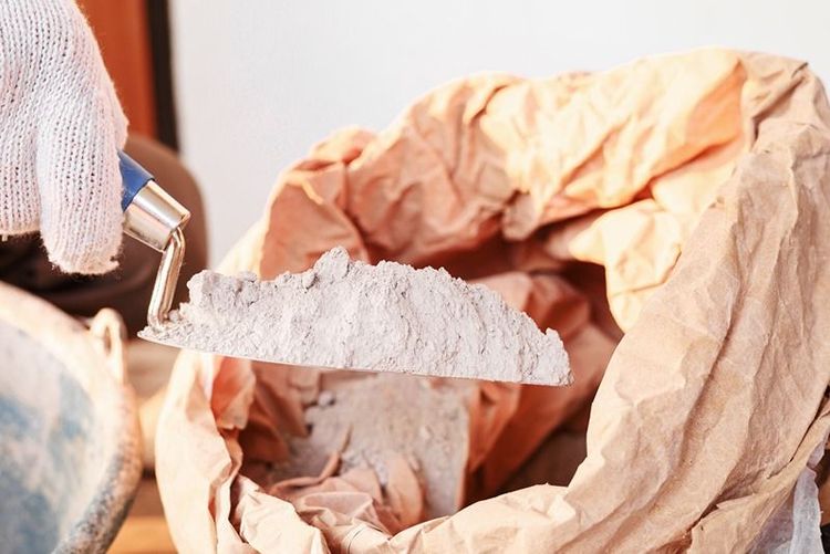 worker_mixing_cement_powder_and_water_on_ground