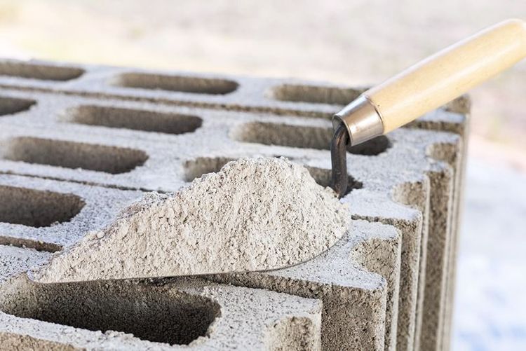 worker_adding_cement_powder_into_mixing_bucket_on_concrete_floor