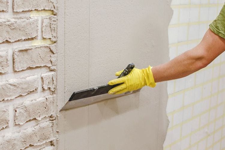 Male_hands_with_spatula_using_putty_for_wall,_builder_making_overhaul.