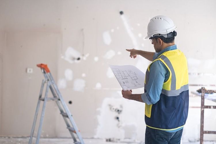 construction_engineer_with_blueprints_pointing_at_building_site