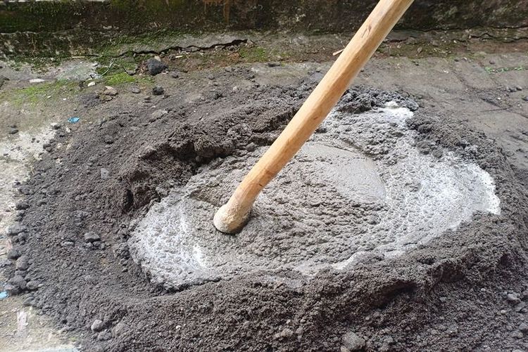 manual_preparation_of_concrete_mixture_with_wooden_tool