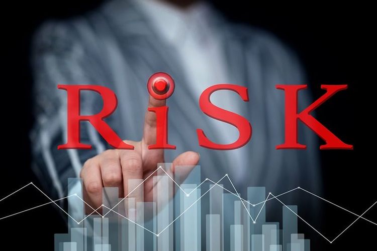 businessman_touching_the_word_risk_with_financial_graphs_in_the_background