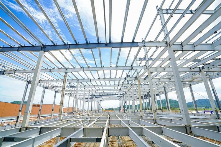 partially_constructed_peb_warehouse_with_steel_frame_and_wooden_beams_on_ground