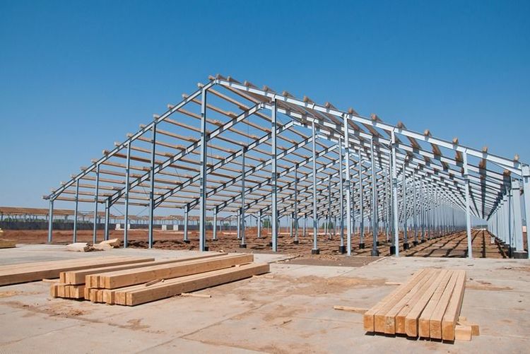 interior_view_of_peb_structure_showing_steel_beams_and_open_roof_design_with_blue_sky_background