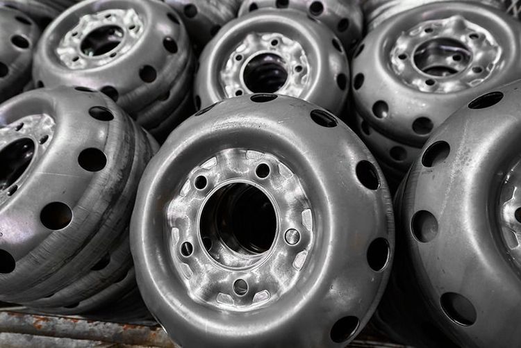pile_of_steel_wheel_rims_with_circular_cutouts_in_factory