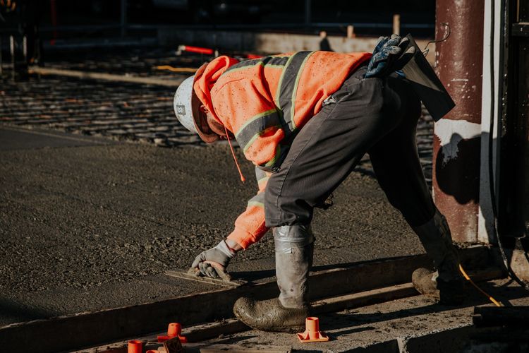 worker_smoothing_concrete_surface_with_tool_at_construction_site